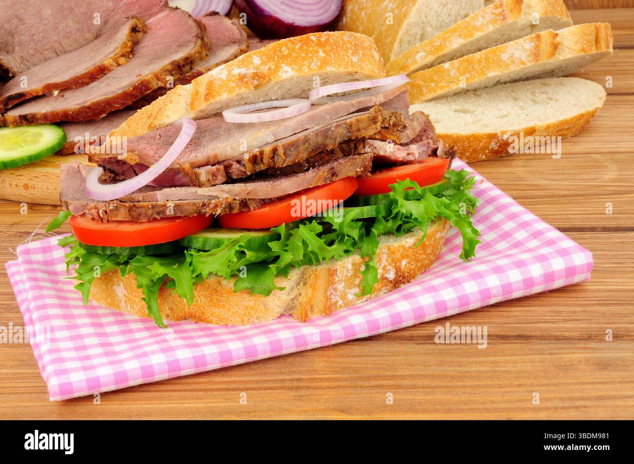 Salat-Sandwich aus Rinderbraten mit Zutaten auf Holzhintergrund Stockfoto