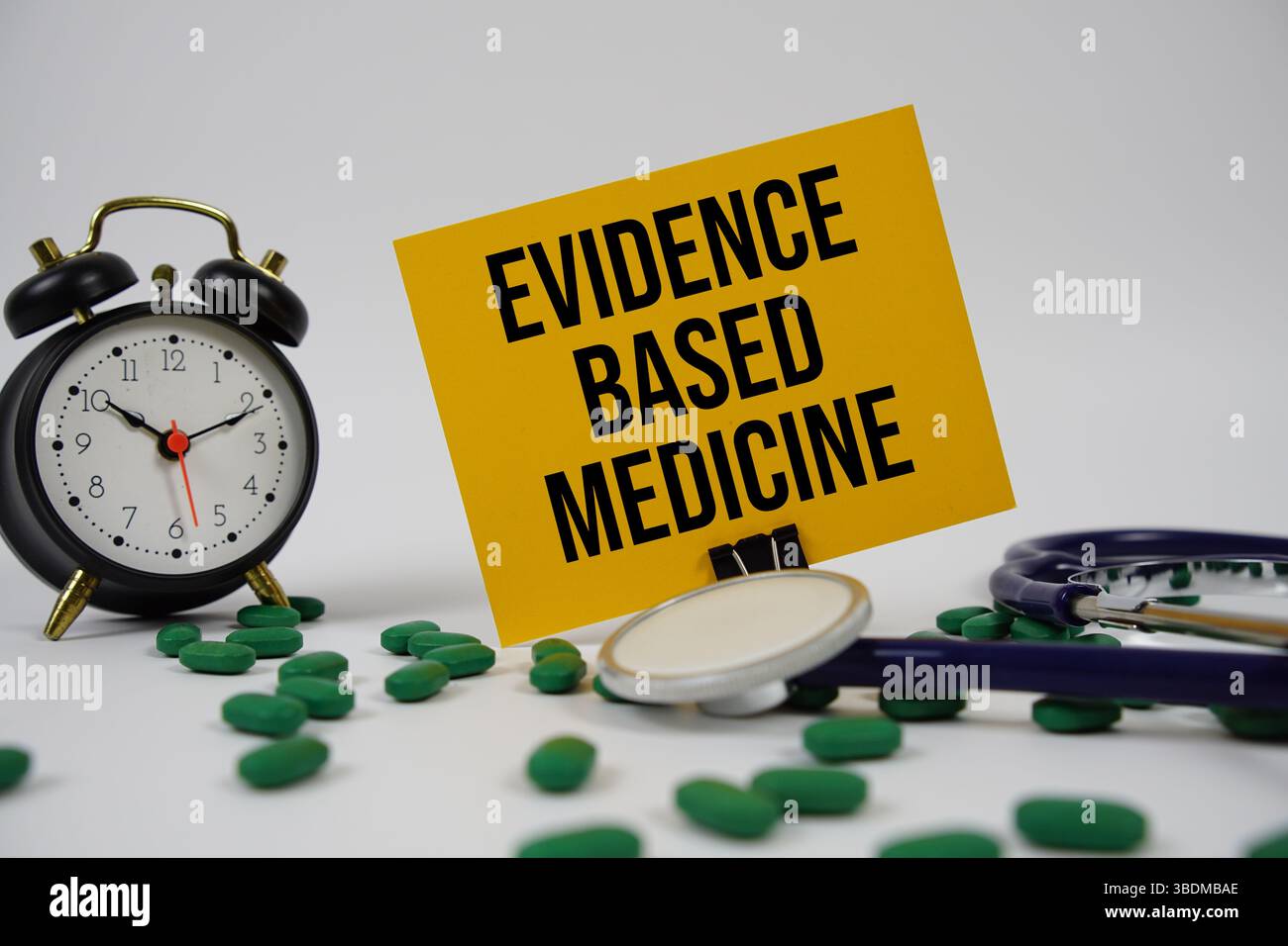 Evidenzbasierter Medizintext mit Wecker und Stethoskop auf weißem Hintergrund Stockfoto