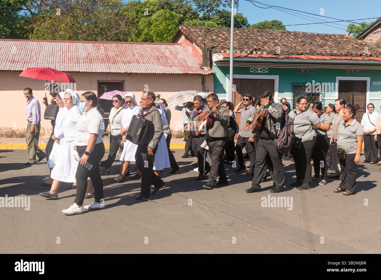 Trauernde, einige mit Musikinstrumenten, gehen hinter einem Pferdewagen in Granada, Nicaragua. Stockfoto
