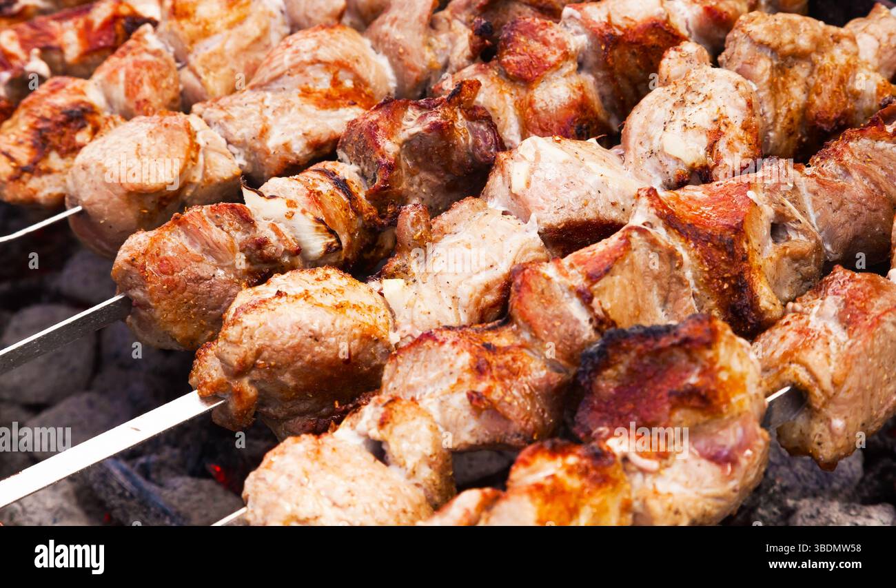 Das Fleisch wird in Nahaufnahme auf einem Gitter über Holzkohle gegrillt. Stockfoto