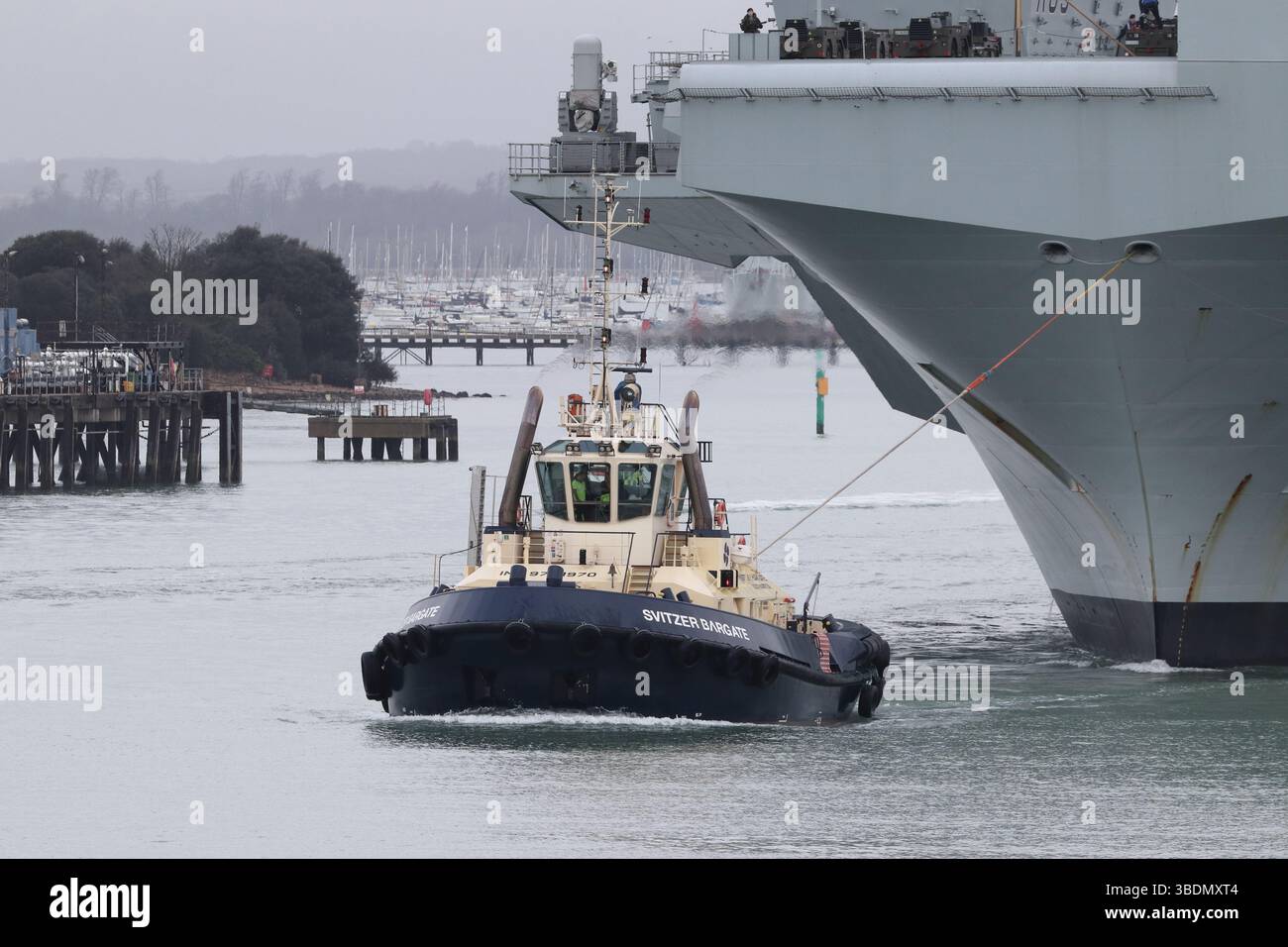 Der Schlepper MV SVITZER BARGATE mit Sitz in Southampton wird in der nahe gelegenen Marinebasis eingesetzt, um den Flugzeugträger HMS PRINCE OF WALES ZU bewegen Stockfoto