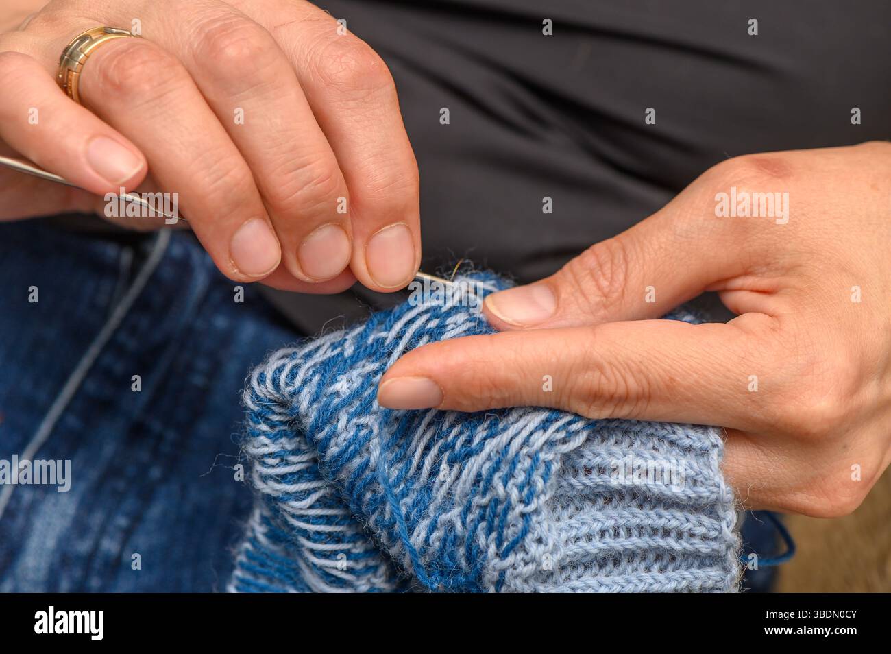 Eine Frau strickt bunte Socken mit einem wunderschönen Muster bei natürlichem Licht, Nahaufnahme der Hände. Stockfoto