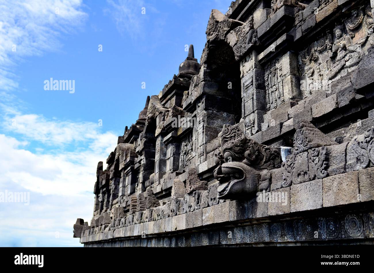 Antike Steinreliefs und Buddha-Statuen zieren die majestätischen Mauern des Borobudur-Tempels, einem buddhistischen Denkmal aus dem 9. Jahrhundert in Indonesien. Stockfoto