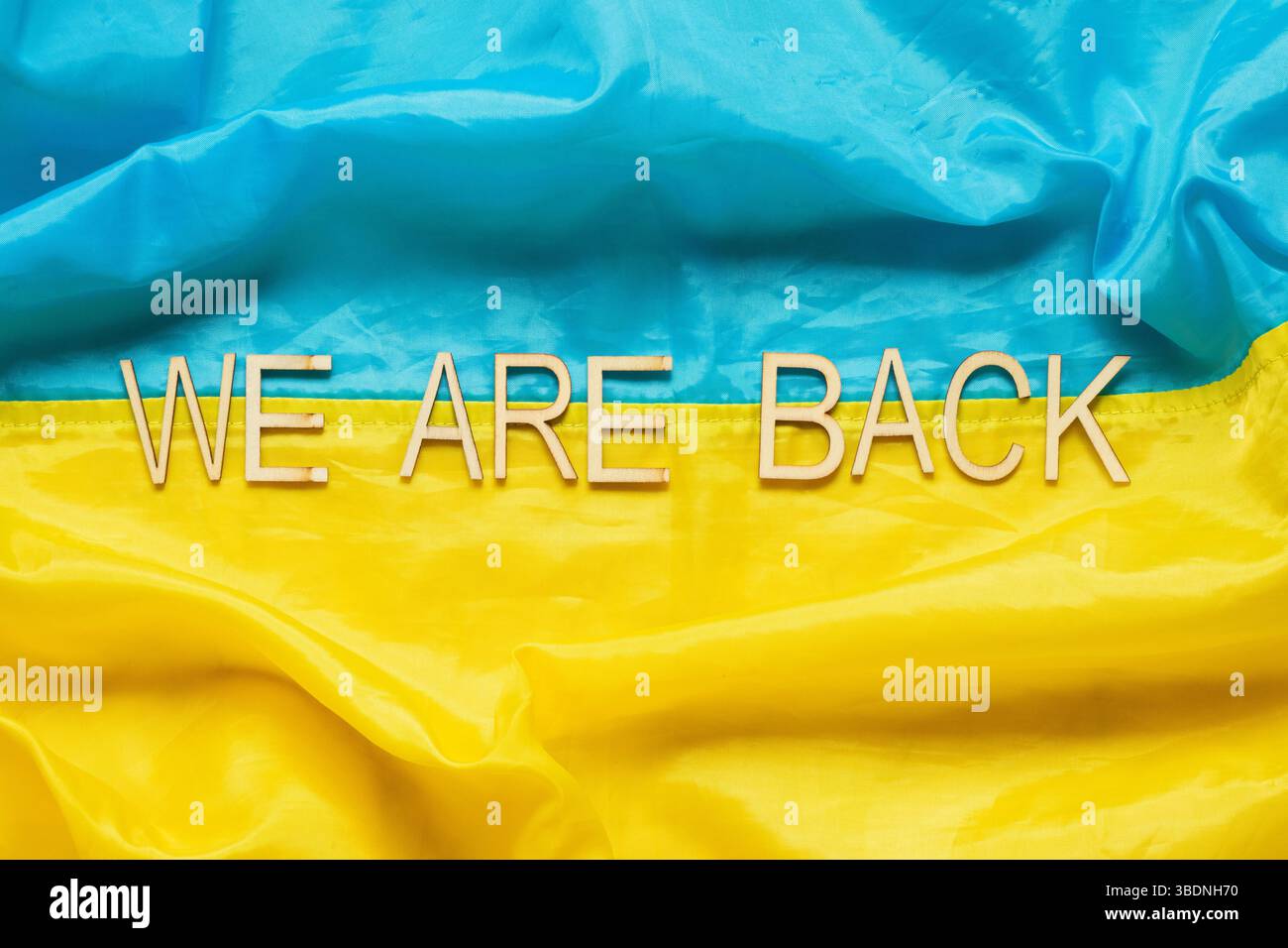 Flagge der Ukraine mit der Aufschrift Wir sind zurück, Symbol für die Rückkehr der gefangenen Helden aus russischen Gefängnissen in die Ukraine Stockfoto