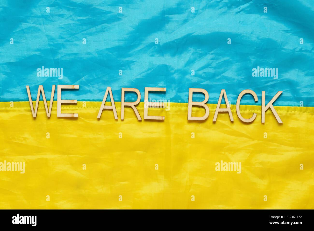 Flagge der Ukraine mit der Aufschrift Wir sind zurück, Symbol für die Rückkehr der gefangenen Helden aus russischen Gefängnissen in die Ukraine Stockfoto