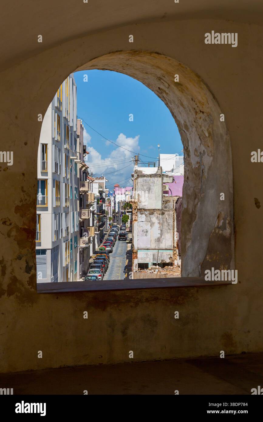 Enge Straße in der Altstadt von Puerto Rico durch eine bogenförmige Öffnung in der Wand des Castillo San Cristobal Stockfoto