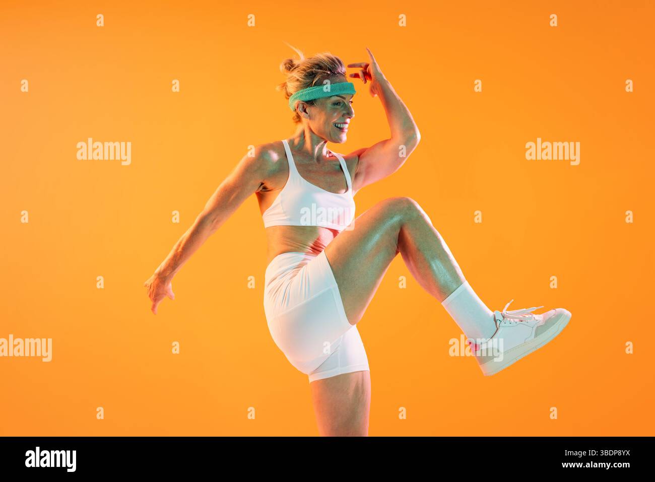 Schöne reife sportliche Frau, die Sportswear trägt, beim Training - muskulöse reife Frau, die dynamische Fitness-Übung durchführt. Glitzernd vor Sweat ag Stockfoto