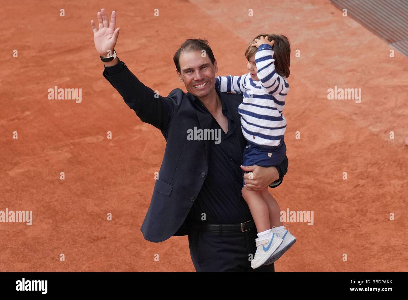 Rafa Nadal waves as he holds his son Rafael Junior during a farewell ceremony at center court Philippe-Chatrier, at the Roland-Garros stadium, in Paris, Sunday May 25, 2025. (AP Photo/Christophe Ena) Stockfoto