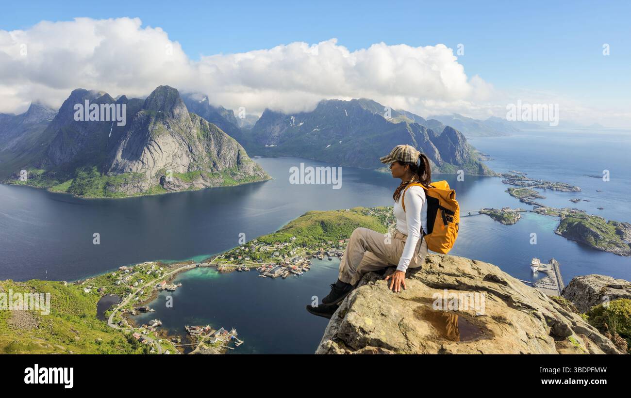 Der Wanderer genießt vom Gipfel des Reinebringen einen atemberaubenden Panoramablick auf die reine und die majestätischen Lofoten. Der klare Himmel und die lebendige Landschaft machen dies zu einem perfekten Ausflug in die Natur. Stockfoto
