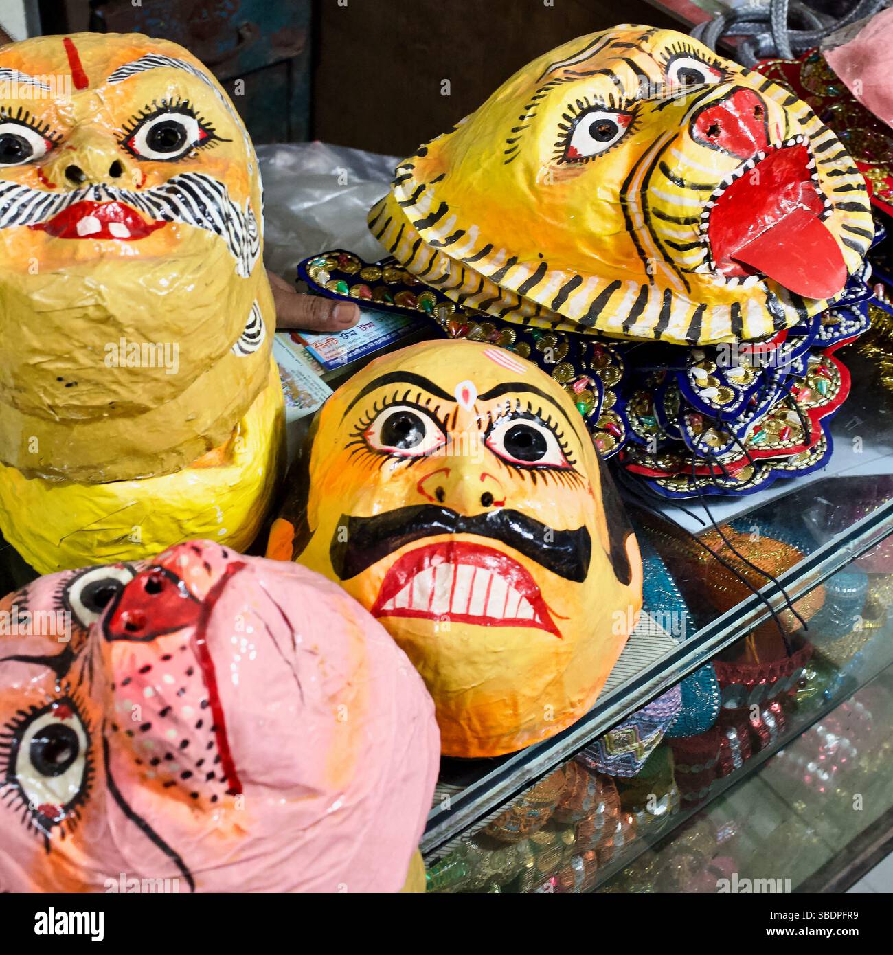 Nahaufnahme der hell bemalten Pappmasken mit mâché hinduistischen Ritualmasken, einschließlich Tigern und Dämonen, die im Shankhari Basar, Old Dhaka, Bangladesch, verkauft werden. Stockfoto