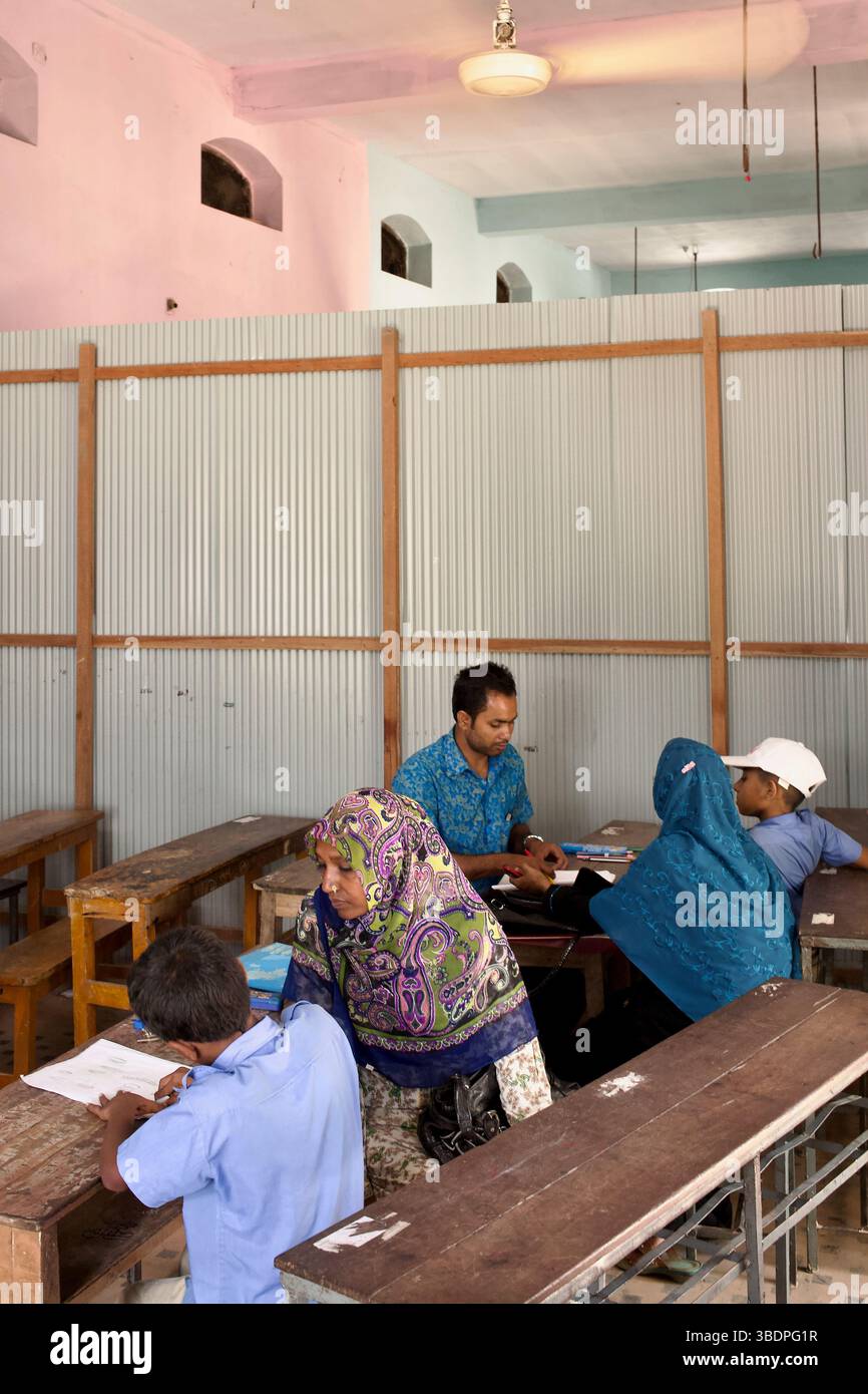 Im Inneren von Rokia Mahal unterstützt ein Lehrer Schüler in einem provisorischen Klassenzimmer, das innerhalb eines abgetrennten Raums im umgenutzten Zamindar-Anwesen eingerichtet ist. Stockfoto