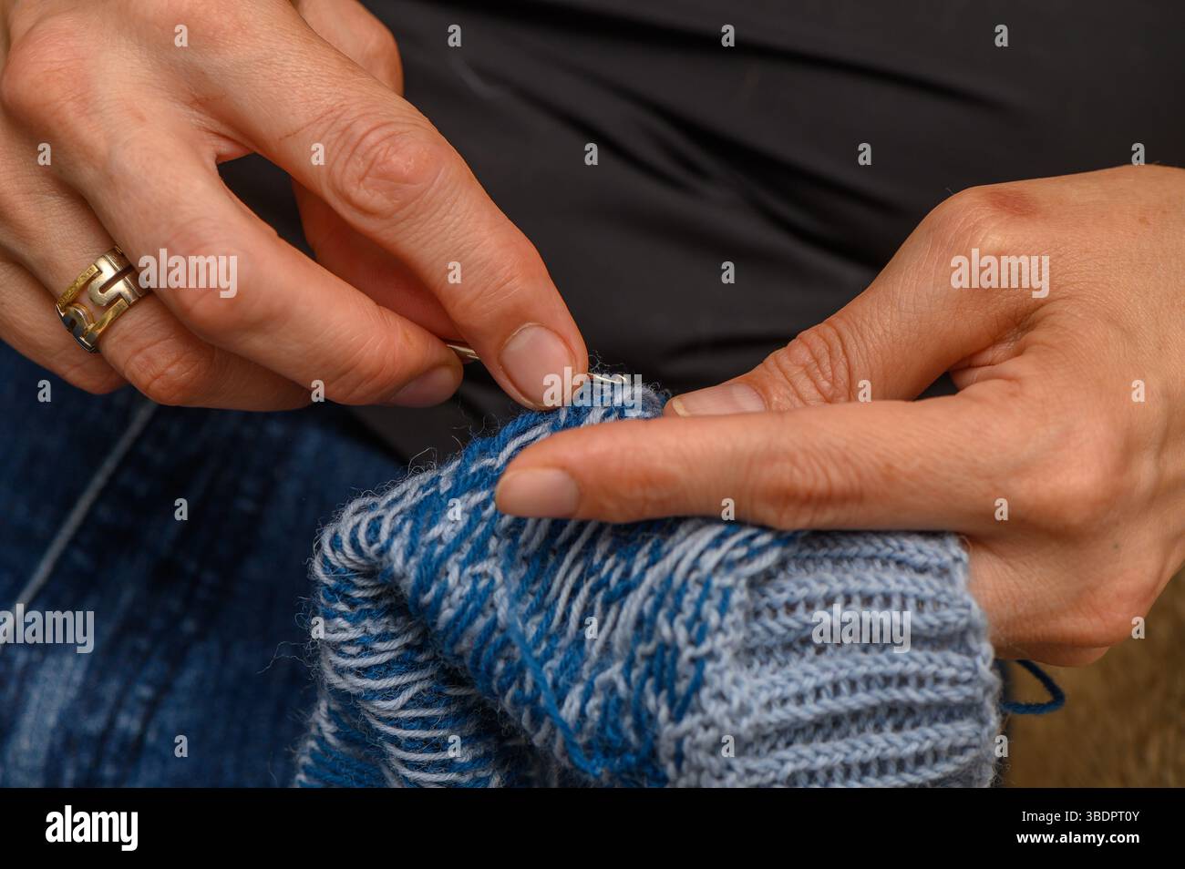 Die Hände einer Frau stricken Wollsocken mit traditionellem Muster, kuscheliger und detailreicher Handwerkskunst. Stockfoto