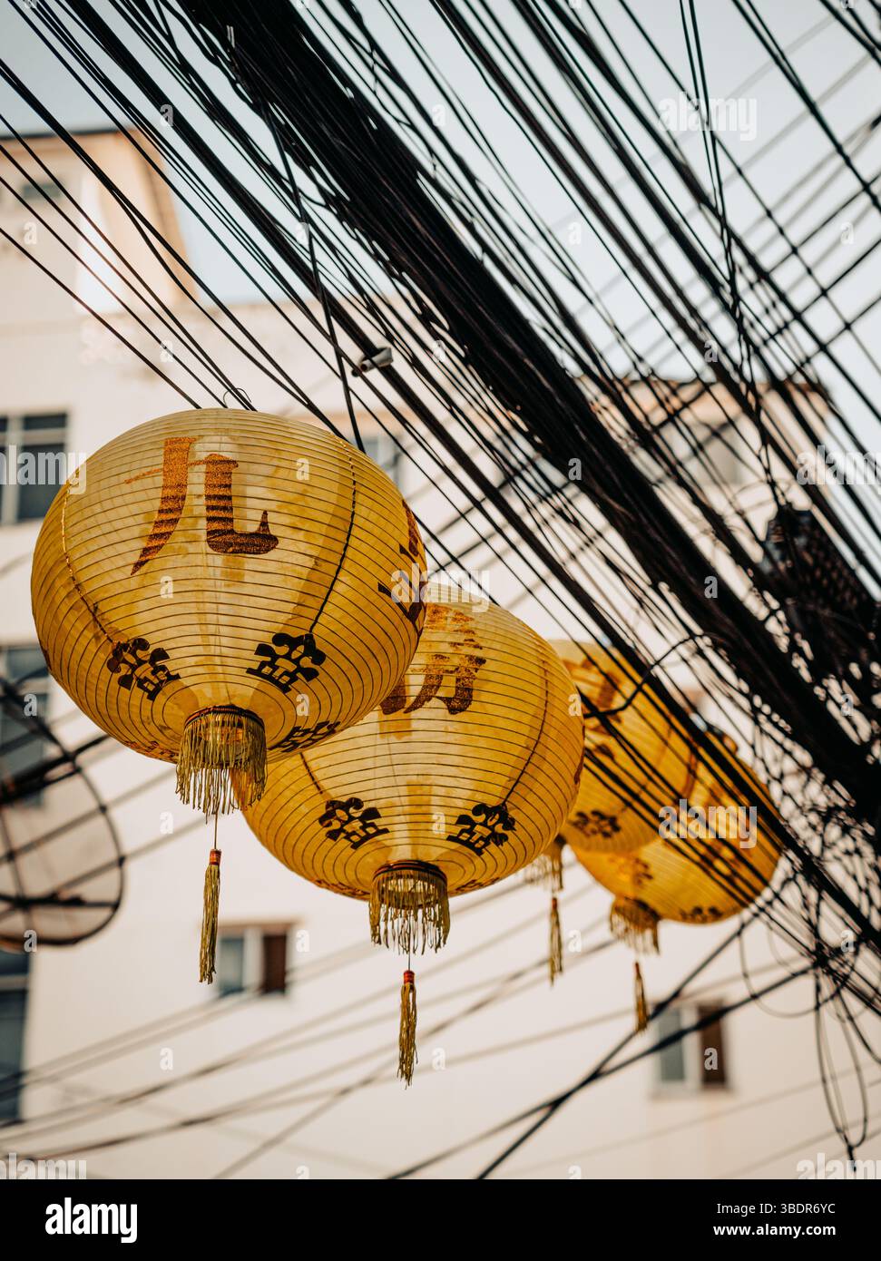 Urbane Thai-Szene mit Khom Pha-Laternen, die an Stromleitungen hängen und die traditionelle thailändische Kultur zeigen Stockfoto