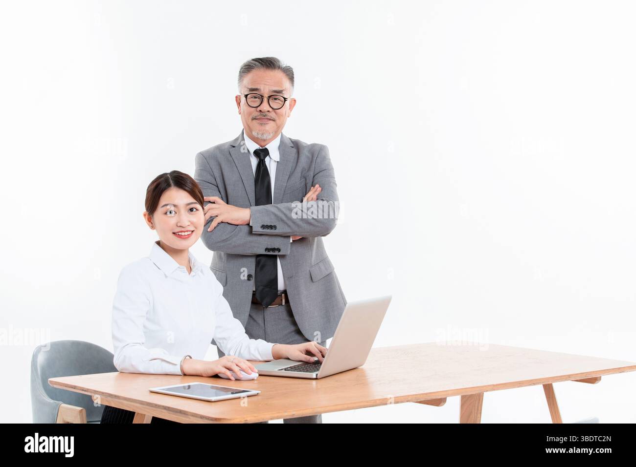 Ein geschäftlicher älterer Mann und eine junge Frau stehen (sitzend) am Schreibtisch Stockfoto