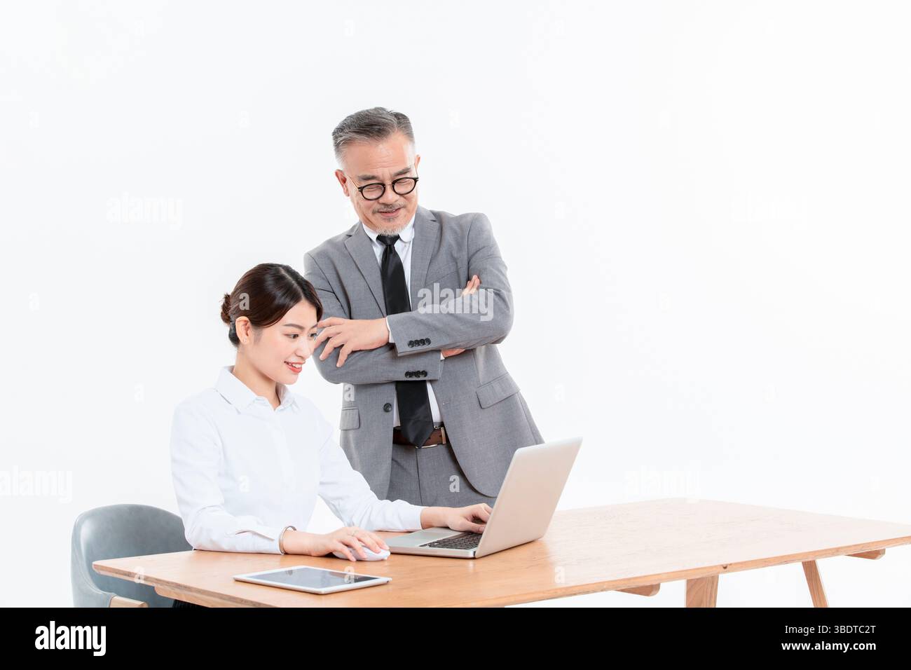 Ein geschäftlicher älterer Mann und eine junge Frau stehen (sitzend) am Schreibtisch Stockfoto