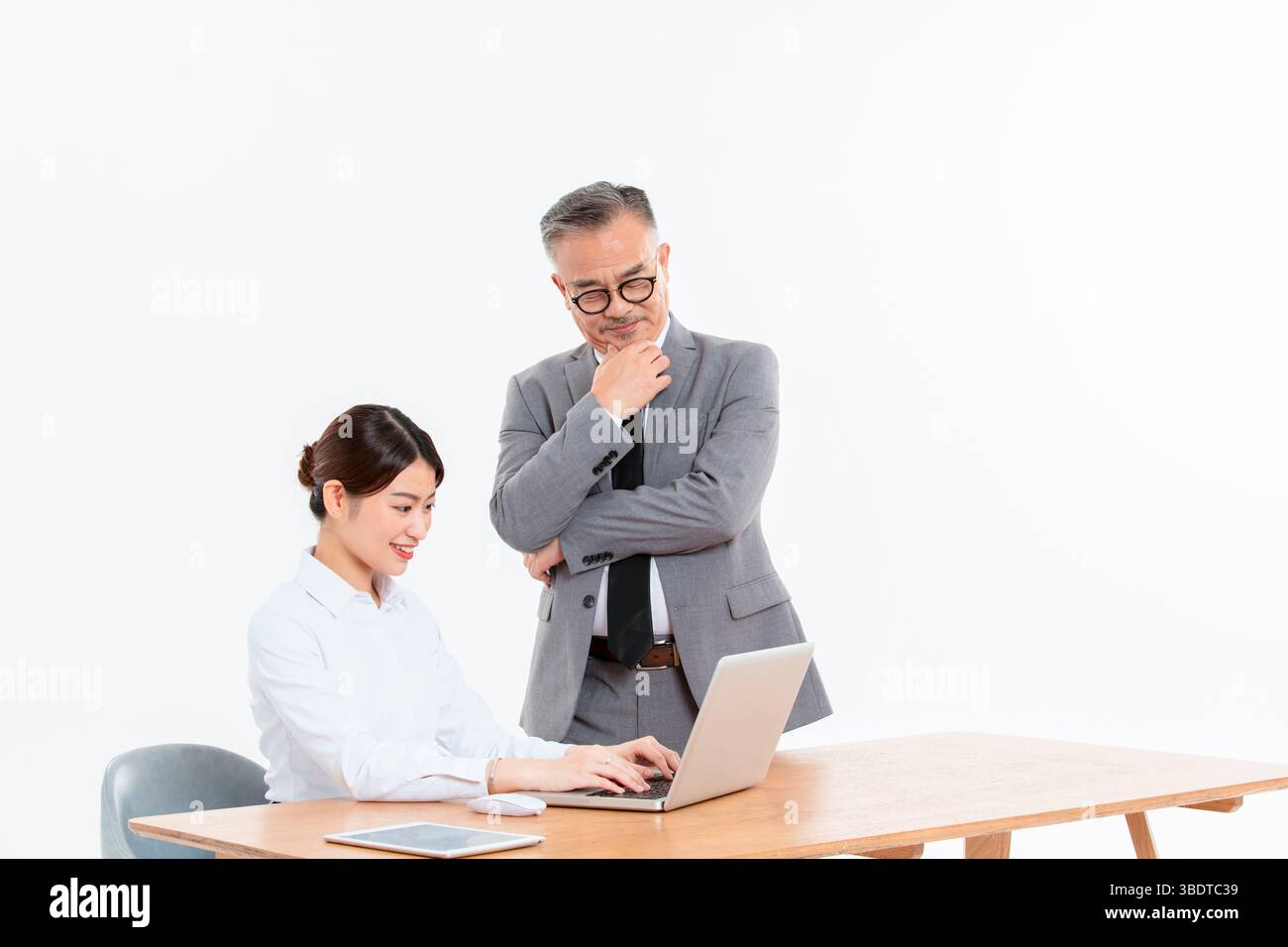 Ein geschäftlicher älterer Mann und eine junge Frau stehen (sitzend) am Schreibtisch Stockfoto