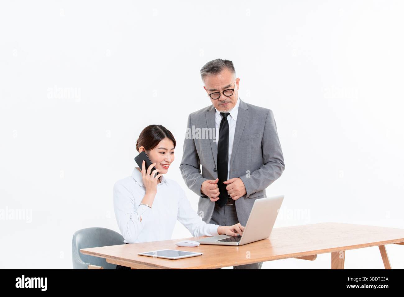Ein geschäftlicher älterer Mann und eine junge Frau stehen (sitzend) am Schreibtisch Stockfoto