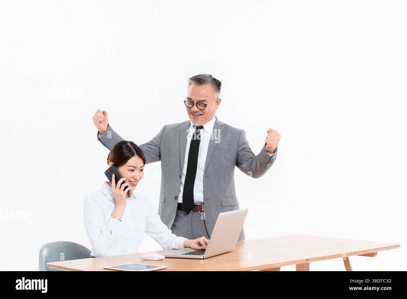 Ein geschäftlicher älterer Mann und eine junge Frau stehen (sitzend) am Schreibtisch Stockfoto