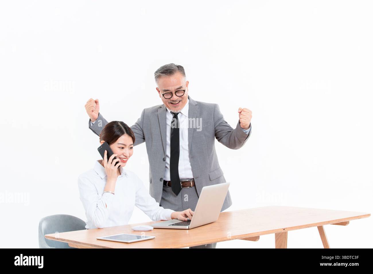 Ein geschäftlicher älterer Mann und eine junge Frau stehen (sitzend) am Schreibtisch Stockfoto