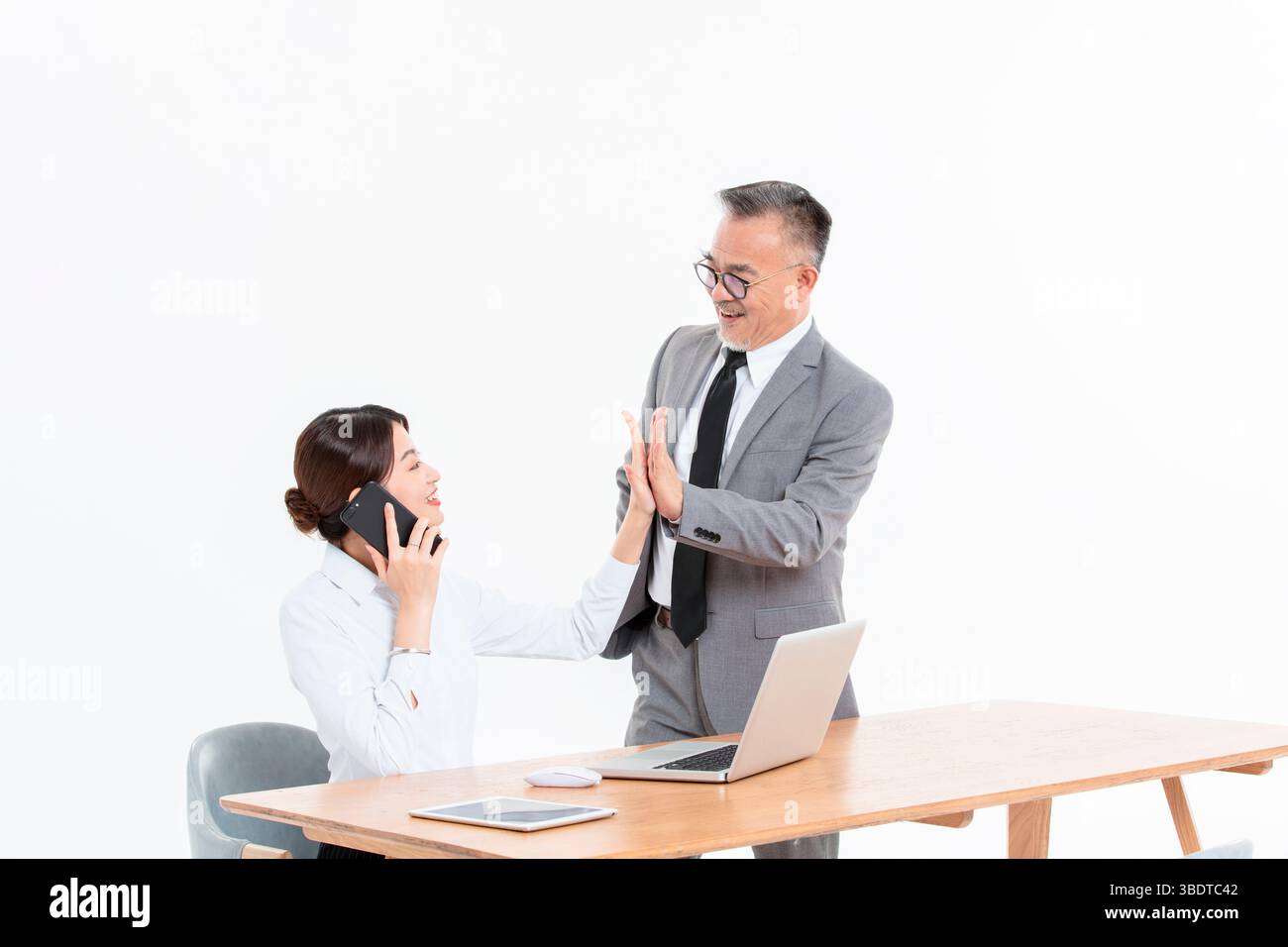 Ein geschäftlicher älterer Mann und eine junge Frau stehen (sitzend) am Schreibtisch Stockfoto