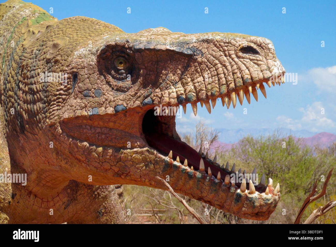 Dinosaurier im Wüstenland. Die Statue, ein Modell-Dinosaurier, der auf einem roten trockenen Sand zwischen den Felsen steht. Künstlicher Dinosaurier. Jurassic Park. Modelle Dino Stockfoto