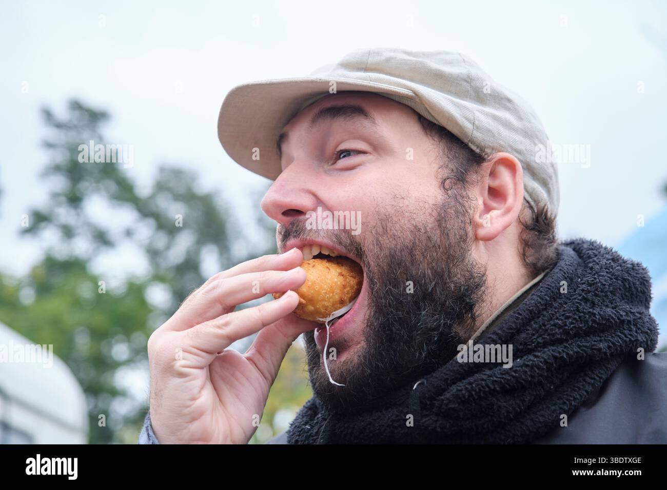 Junger Mann genießt im Freien frisch zubereitete Empanada aus argentinischem Schinken und Käse. Stockfoto