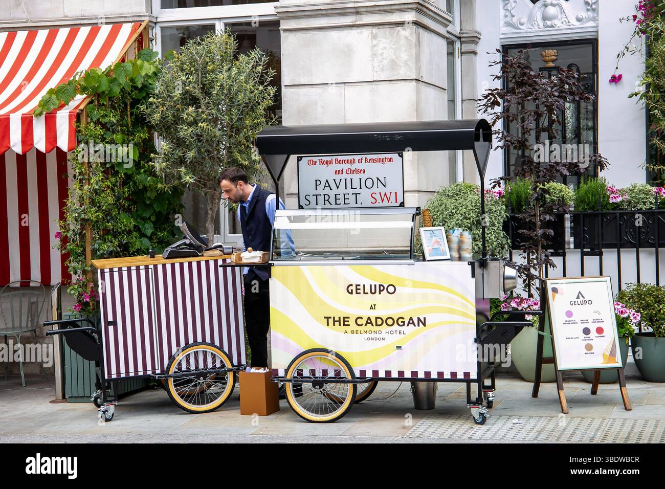 Straßenverkäufer, der an einem sonnigen Tag Gelato aus einem mobilen Wagen vor einem stilvollen Londoner Hotel verkauft. Stockfoto