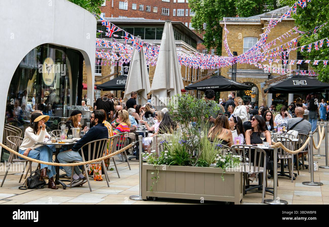 Café-Szene im Freien mit Leuten, die unter dekorativen Häppchen Speisen und Getränke genießen, auf einem belebten stadtplatz Stockfoto
