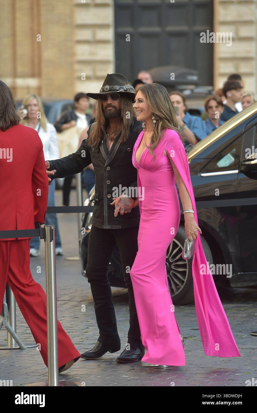Italien, Rom, 24. Mai 2025 - Liz Hurley betäubt sich in einem rosa Outfit, als sie Hand in Hand mit ihrem Partner Billy Ray Cyrus auf ihrem ersten Gesellschaftsausflug zusammen mit Liz' Sohn Damian Charles Hurley auf dem roten Teppich zur Eröffnung der Orizzonti/Rosso-Ausstellung von Valentino Garavani und Giancarlo Giammetti in Rom geht. Foto © Fabio Mazzarella/Sintesi/Alamy Live News Stockfoto