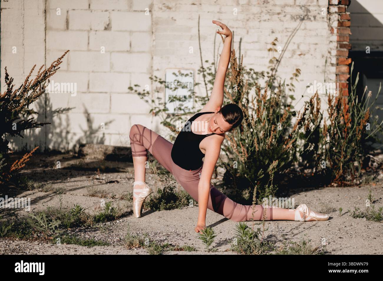 Tänzerin in Spitzenschuhen auf einem überwachsenen Stadtplatz Stockfoto