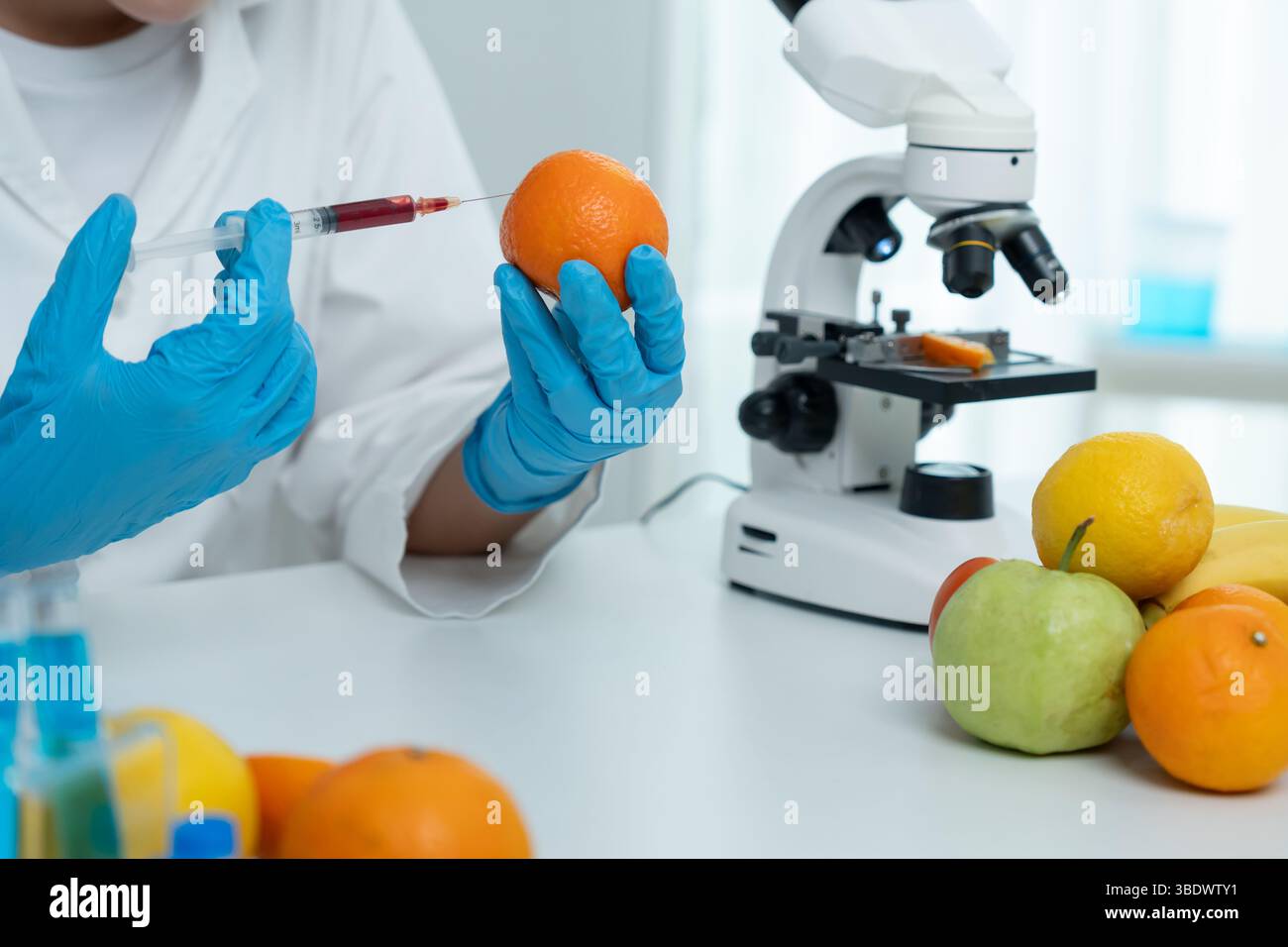 Wissenschaftler überprüfen chemische Lebensmittelrückstände im Labor. Kontrollexperten prüfen die Qualität von Früchten, Wissenschaftler injizieren Chemikalien in Äpfel für Experimente Stockfoto