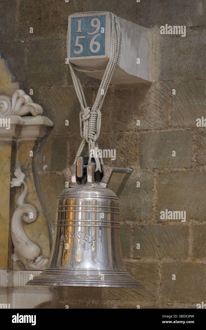 Elegante silberne Sussex-Glocke hängt an einer verzierten Steinmauer, 1956 Datum hervorgehoben. Chichester, Großbritannien Stockfoto