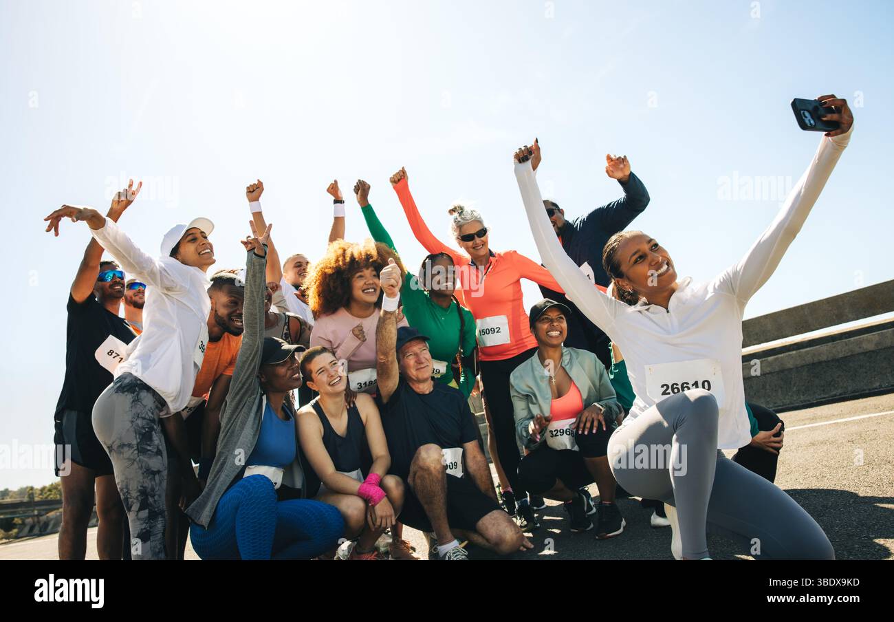 Eine fröhliche Gruppe von Läufern fängt nach einem Rennen einen festlichen Moment mit einem Selfie ein. Die Teilnehmer sind voller Energie und Einheit und zeigen ihre Einheit Stockfoto