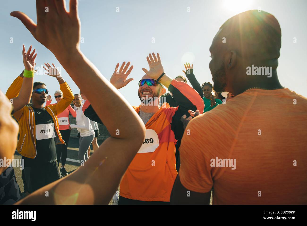 Ein freudiger Moment, in dem sich eine Gruppe von Läufern nach Abschluss einer Veranstaltung austauschen kann. Das Bild vermittelt Teamarbeit unter verschiedenen Teilnehmern an Stockfoto
