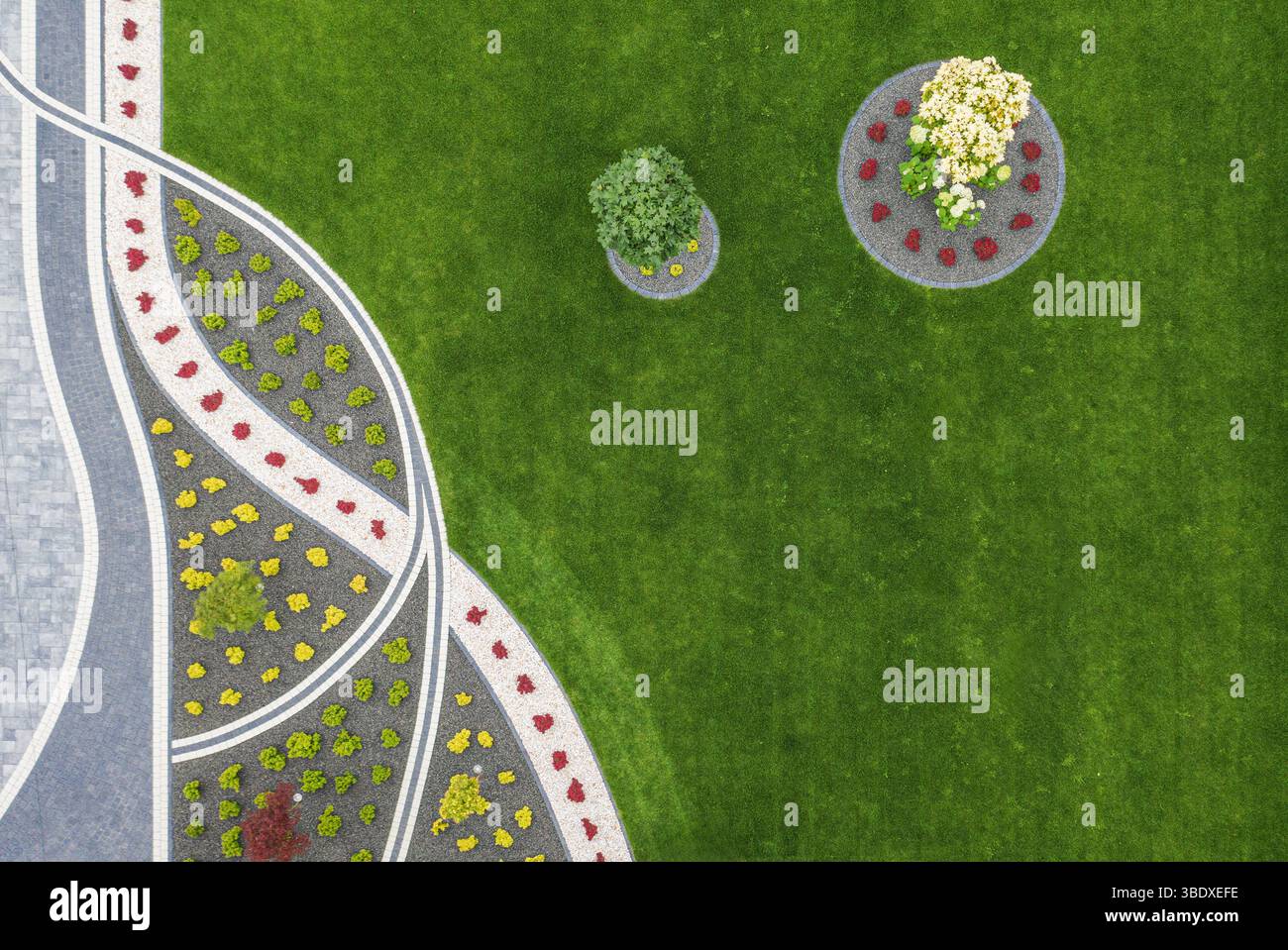 Lebhafte Blumenbeete und üppiges Grün schaffen tagsüber eine einladende Atmosphäre in diesem gut gestalteten Garten mit sorgfältiger Landschaftsgestaltung und Co Stockfoto