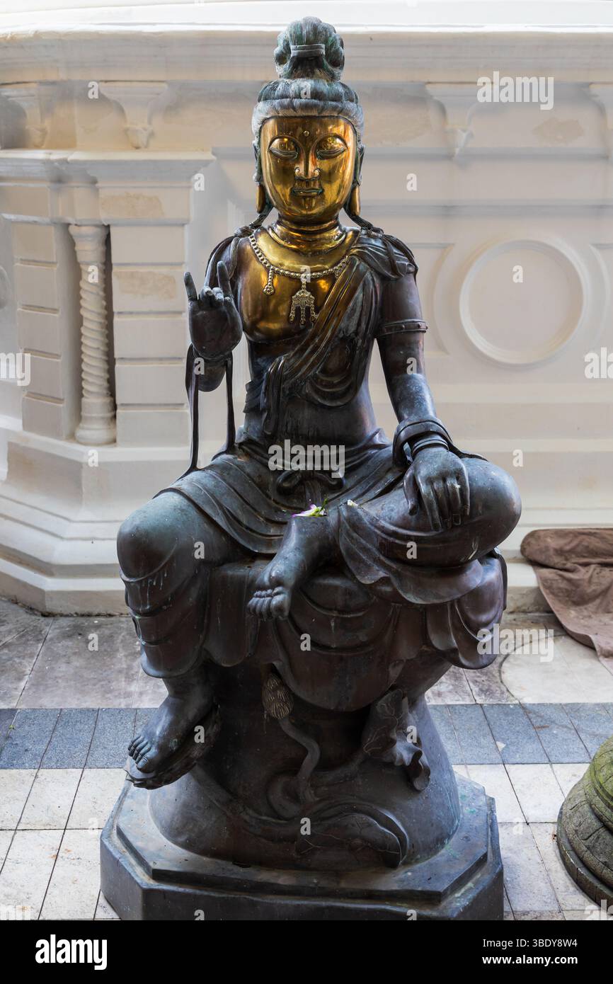 Gangaramaya Tempel, Colombo, Sri Lanka. Eine wunderschöne Buddha-Statue aus Bronze, dargestellt in einer eleganten Sitzhaltung, vor einem detaillierten architektonischen B Stockfoto Gangaramaya Tempel, Colombo, Sri Lanka. Eine wunderschöne Buddha-Statue aus Bronze, dargestellt in einer eleganten Sitzhaltung, vor einem detaillierten architektonischen B Stockfoto