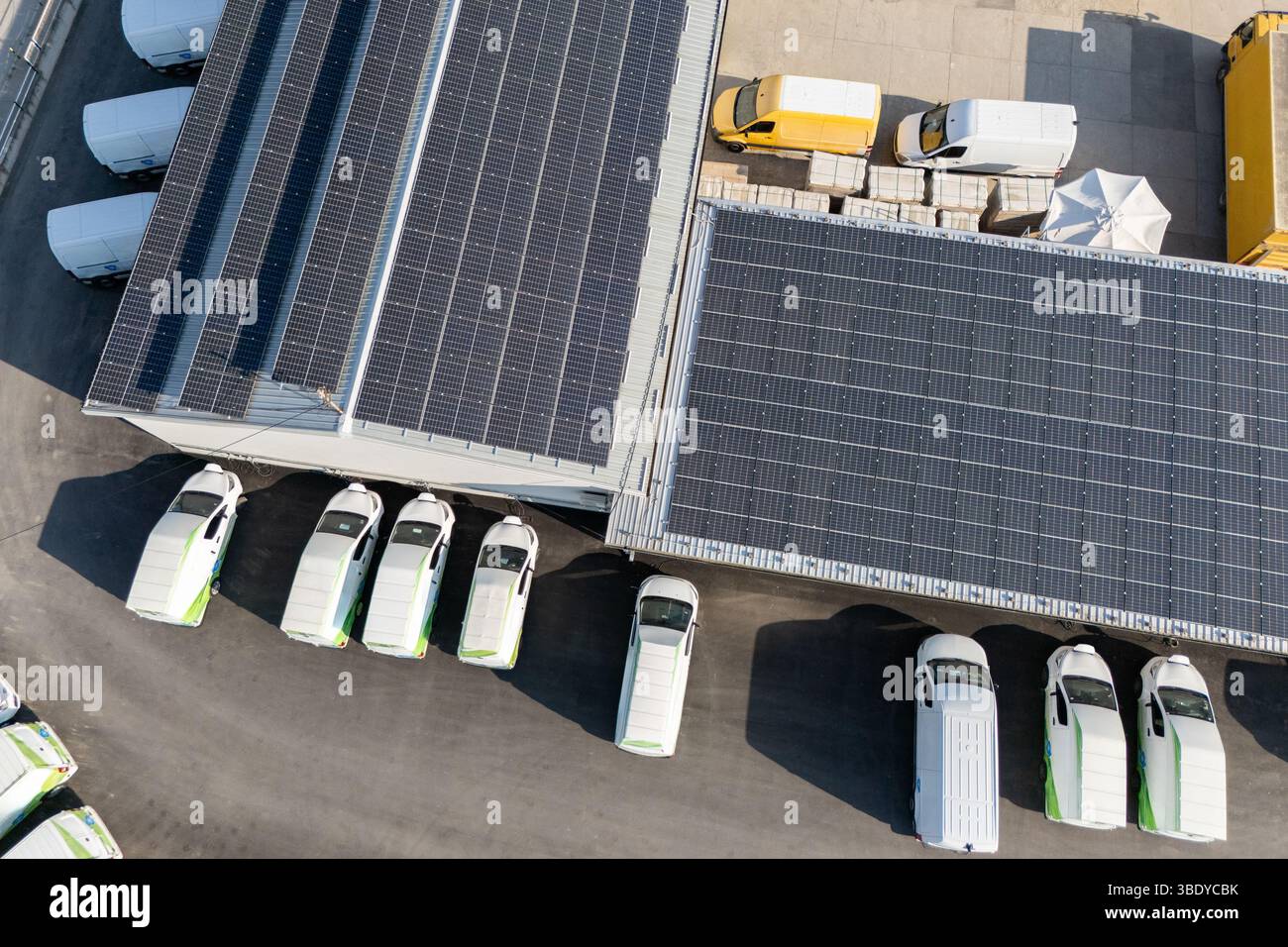 Reihen von weißen Elektro-Lieferwagen an Ladestationen für Elektrofahrzeuge. Stockfoto