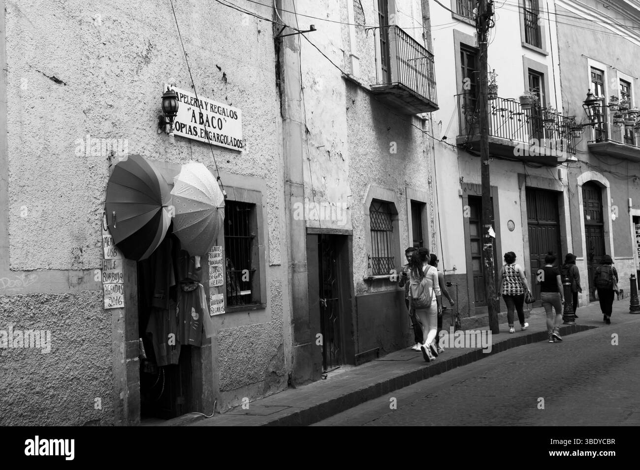 Guanajuato City, Mexiko - 30. Mai 2016: Die Menschen laufen entlang einer Straße mit Geschäften, darunter „Abaco“, die Geschenke und Schulutensilien verkauft. Stockfoto