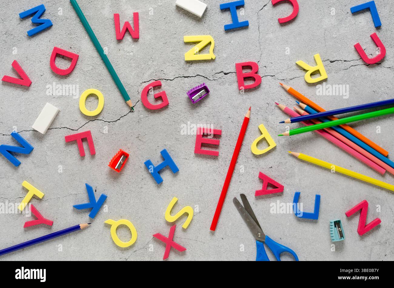 Bunte Alphabetbuchstaben und Schulutensilien auf einer Betonoberfläche. Back-to-School-Konzept. Stockfoto