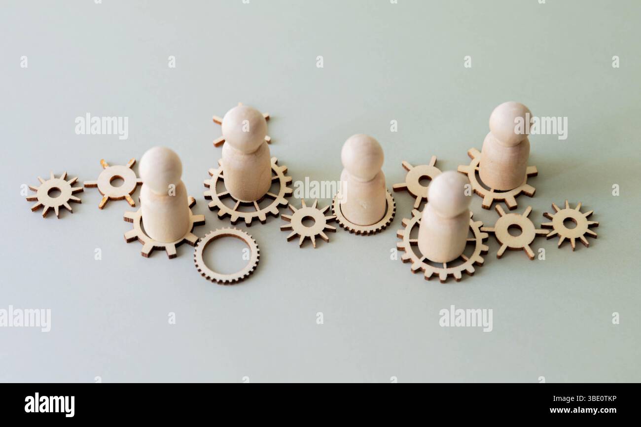 Ein konzeptionelles Bild mit Holzfiguren, die auf miteinander verbundenen Zahnrädern stehen. Teamarbeit, Zusammenarbeit und die Vernetzung des Arbeitskonzepts. Stockfoto