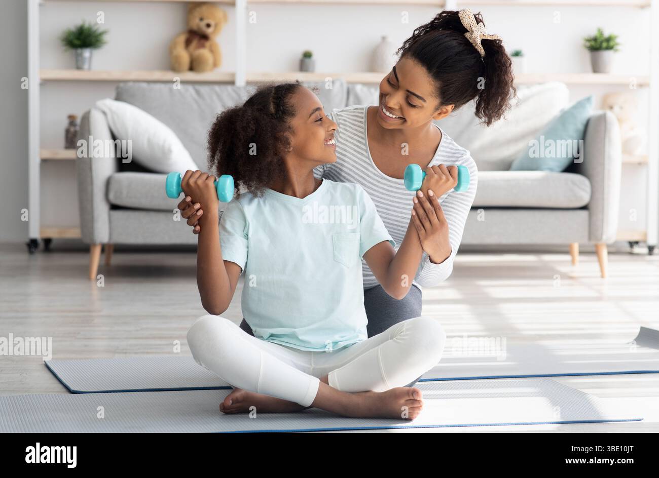Liebevolle afroamerikanische Mutter und Tochter mit Langhanteln Stockfoto