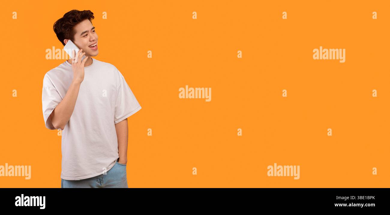 Asian Kerl im Gespräch auf Handy, Blick auf freien Raum Stockfoto