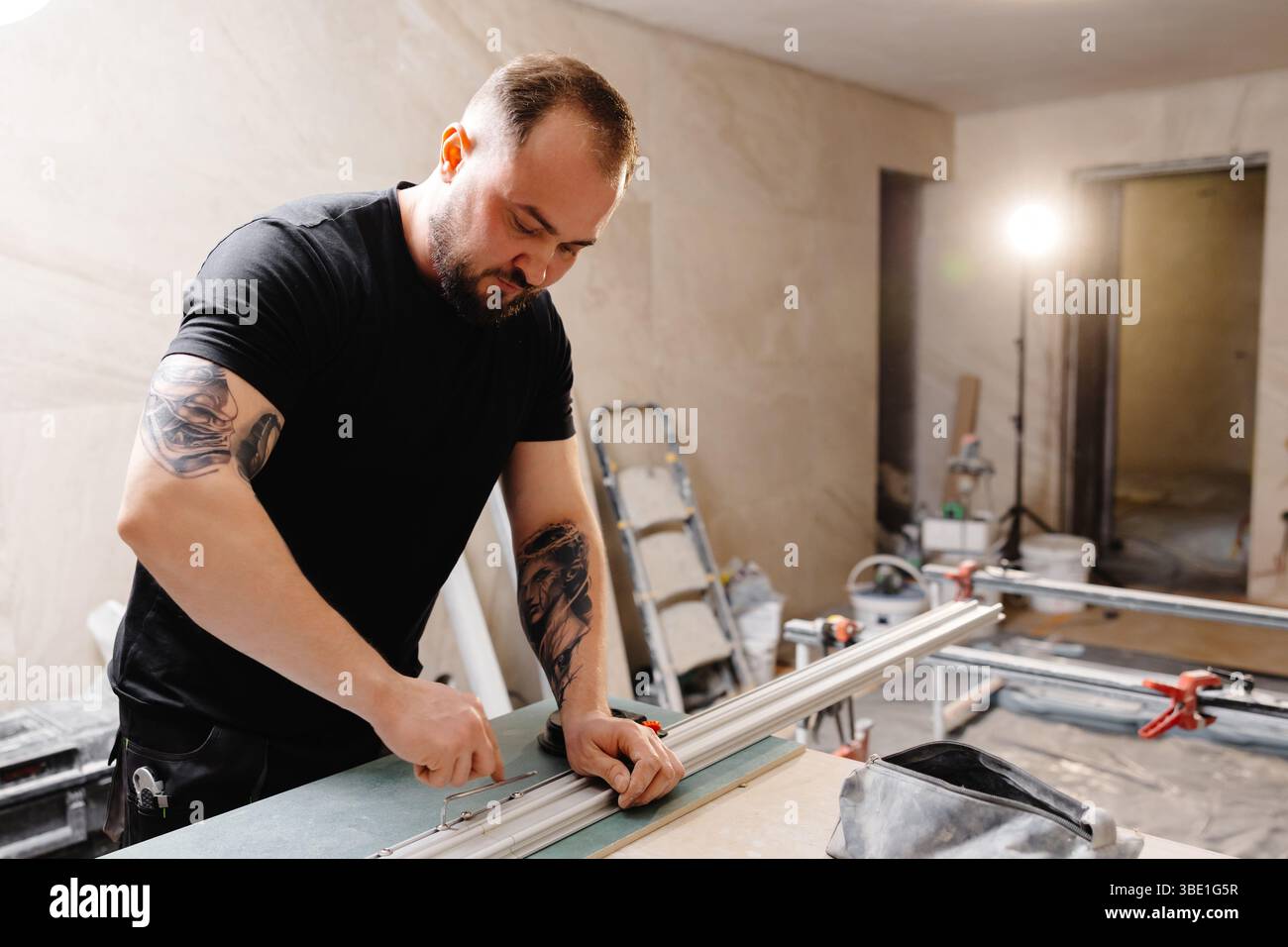 Der Baumeister bereitet Aluminiumprofile für die Dehndecke unter Verwendung spezieller Ausrüstung in der renovierten Wohnung vor Stockfoto