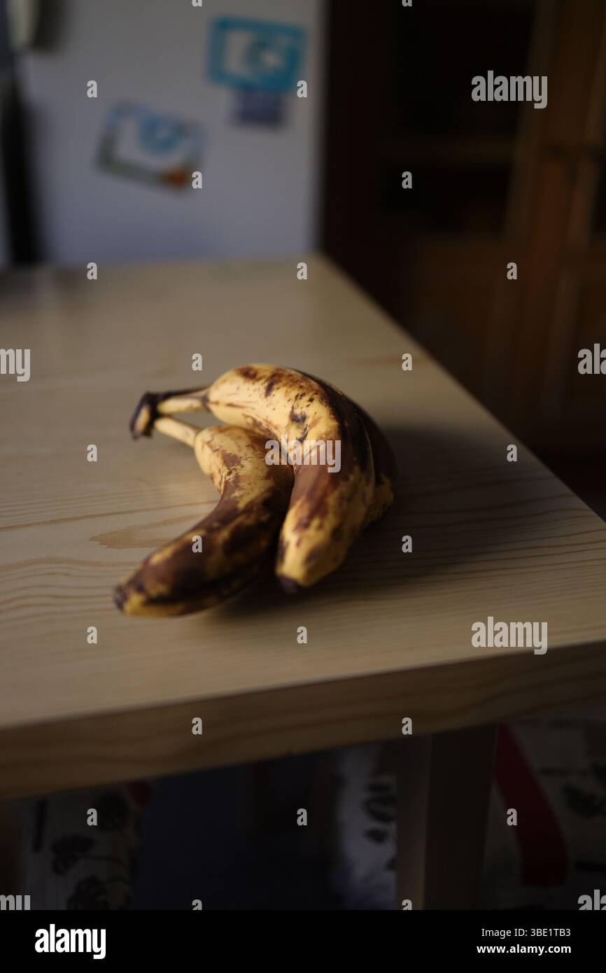 Drei gelbe Bananen auf einem rustikalen Holztisch. Stockfoto