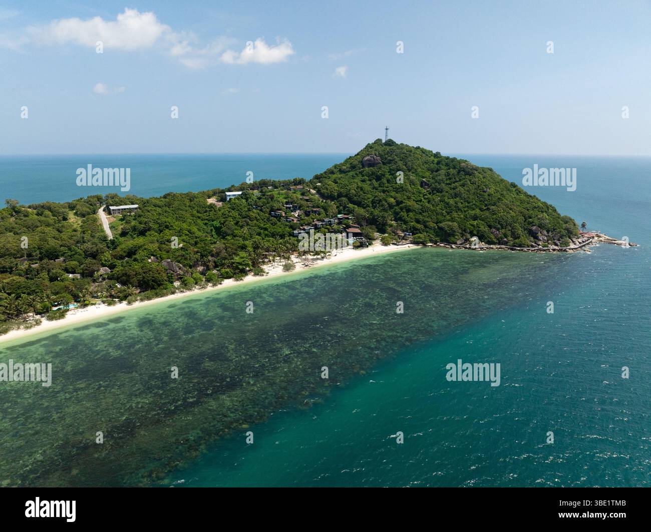 Ein landschaftlich schöner Hügel mit üppigem Grün und Häusern mit Blick auf ein ruhiges türkisfarbenes Meer. Leela Beach. Ko Pha Ngan, Thailand. Stockfoto