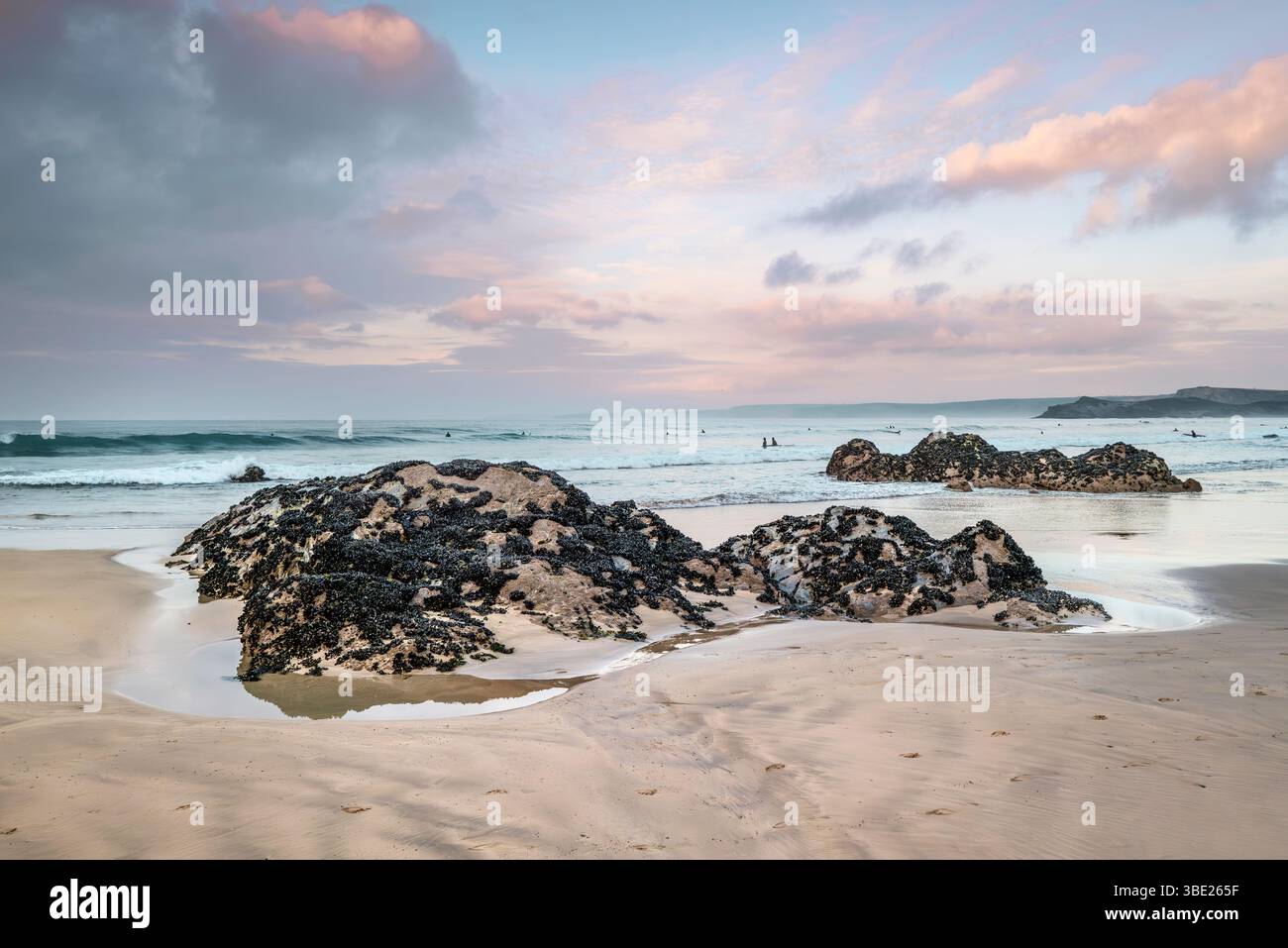 Pastellfarbener Himmel über Felsen, die von Ebbe am GT Western Beach an der Küste von Newquay in Cornwall in Großbritannien freigelegt werden. Stockfoto