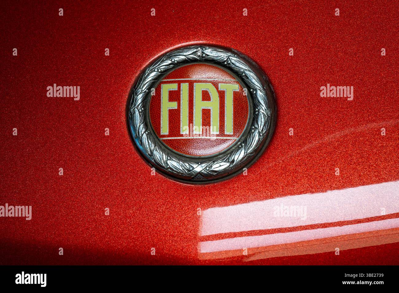 Nahaufnahme eines alten Fiat-Logos, das das historische Emblem der Marke auf einem klassischen roten Auto zeigt Stockfoto