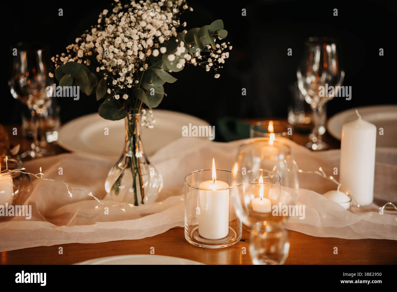 Ein zarter Blumenstrauß, Kerzenlicht und die Holzstruktur des Tisches schaffen eine romantische Atmosphäre. Tischdekoration. Stockfoto
