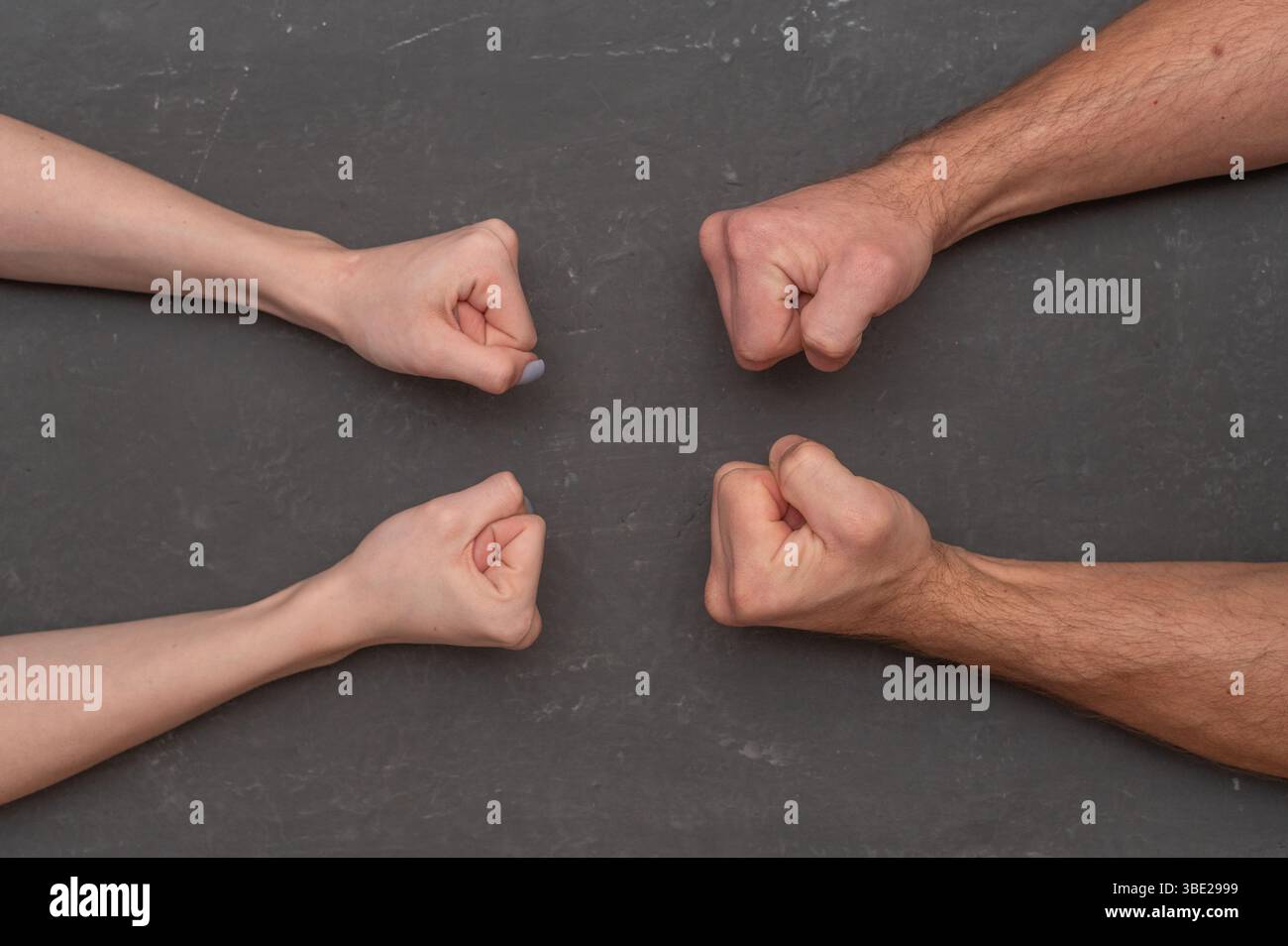 Männer Hände zu einer Faust gegen Frauenfäuste geballt. Konfrontationsbegriff, Konflikt zwischen gegensätzlichen Geschlechtern. Männliche und weibliche Fäuste wieder gedrückt Stockfoto