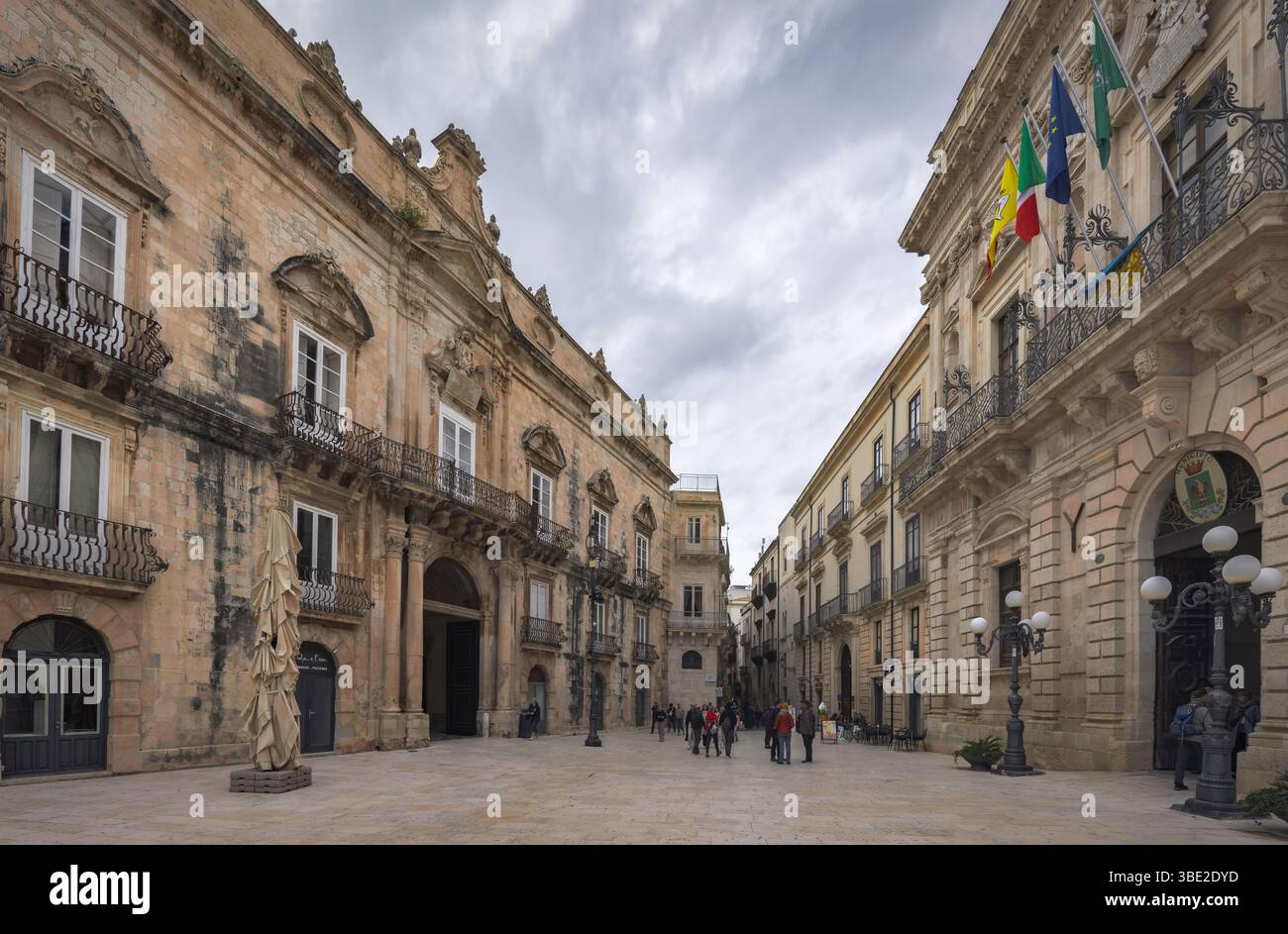 Bei einem Spaziergang durch Ortigia bewundern Besucher die komplexen barocken Gebäude und den dramatischen Himmel, der das Ambiente Siziliens, Italien, unterstreicht Stockfoto